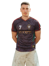 Modelo masculino posando de frente con la camiseta de fútbol Cuotti color negro y verde, con el escudo de Portugal, el número 7 y detalles dorados.