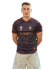 Modelo masculino posando de frente con la camiseta de fútbol Cuotti color negro y verde, con el escudo de Portugal, el número 7 y detalles dorados.